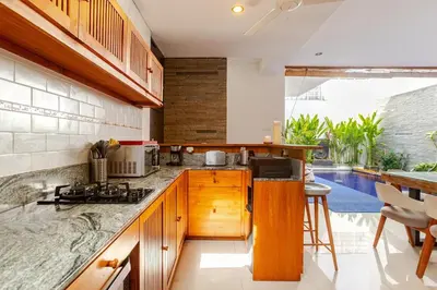 a kitchen with wooden cabinets and a pool at Villa Stephana Edge of Seminyak in Canggu