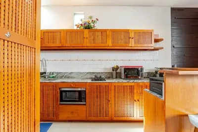a kitchen with wooden cabinets and a microwave at Villa Stephana Edge of Seminyak in Canggu
