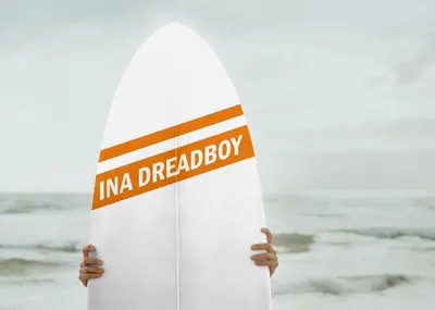 a person holding a surfboard on the beach at inadreadboy surfclass in Legian