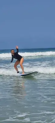 a woman riding a wave on a surfboard in the ocean at inadreadboy surfclass in Legian