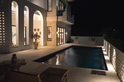 a house with a swimming pool at night at Stunning Sea Front Villa 4BR Nusa Dua in Badung