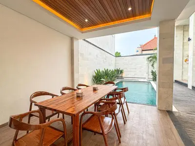 a dining room with a table and chairs and a swimming pool at Olala Loft Seminyak in Seminyak