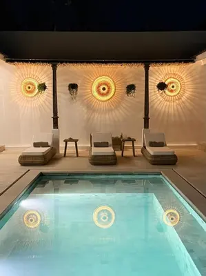 a swimming pool with two beds and two chairs at Villa Gamelan Bohème Chic Bali in Seminyak