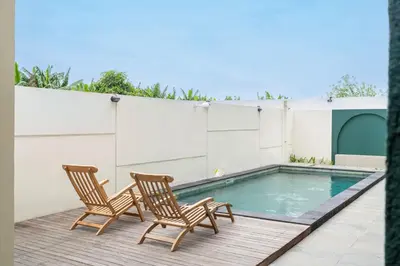 two chairs and a swimming pool on a patio at D'Gangga Residence By Bali Cabin in Kerobokan