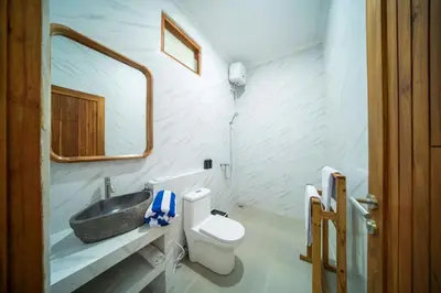 a bathroom with a sink and a toilet and a mirror at D'Gangga Residence By Bali Cabin in Kerobokan