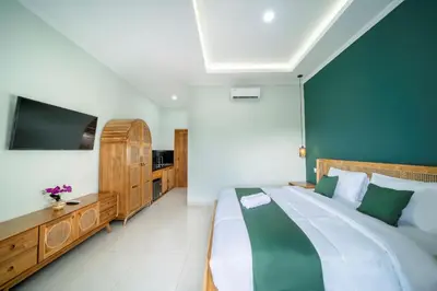 a bedroom with a large bed and a flat screen tv at D'Gangga Residence By Bali Cabin in Kerobokan