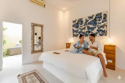 a man and woman sitting on a bed in a bedroom at Villa Sitara, Sitara Villa Group in Seminyak