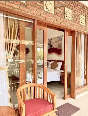 a room with a bedroom with a bed and a chair at Wresni guesthouse in Canggu