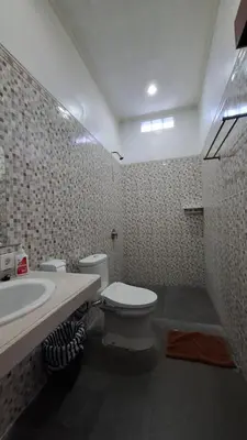a bathroom with a white toilet and a sink at Wresni guesthouse in Canggu