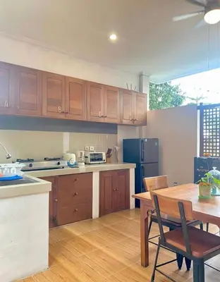 a kitchen with wooden cabinets and a table and a refrigerator at Wresni guesthouse in Canggu