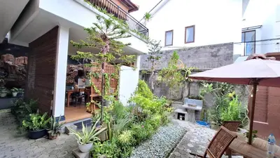 an outdoor patio with plants and an umbrella at Wresni guesthouse in Canggu