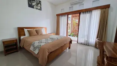 a bedroom with a bed and a large window at Wresni guesthouse in Canggu