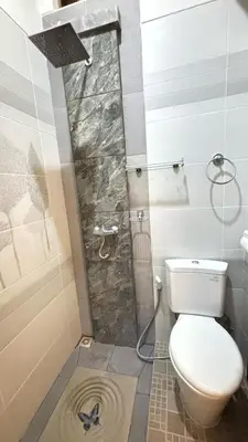 a small bathroom with a toilet and a shower at Graha Shanti Guest House in Pulau Serangan