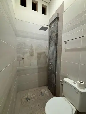 a bathroom with a toilet and a shower at Graha Shanti Guest House in Pulau Serangan