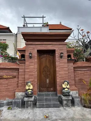 a brick building with a wooden door with teddy bears at Graha Shanti Guest House in Pulau Serangan