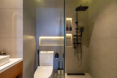 a bathroom with a shower with a toilet and a sink at 1BR Modern Loft near Airport in Pesanggaran