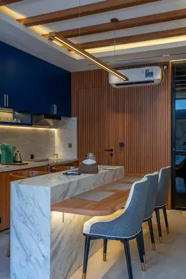 a kitchen with blue walls and a counter with chairs at 2BR Modern Suites near Airport in Pesanggaran