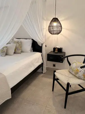 a bedroom with a bed and a chair and a lamp at Villa Casa Mari in Seminyak