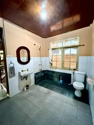 a bathroom with a toilet and a sink and a window at Nyoman Legian House in Legian