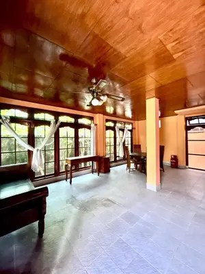 a large living room with a ceiling fan and windows at Nyoman Legian House in Legian