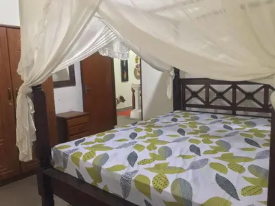 a bedroom with a bed with a canopy at Nyoman Legian House in Legian