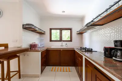 a large kitchen with wooden cabinets and a sink at 10 Bedroom Villa Vista Seminyak in Seminyak
