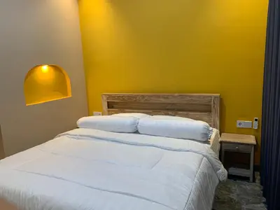 a bedroom with a white bed with a yellow wall at Pradantara House in Nusa Dua