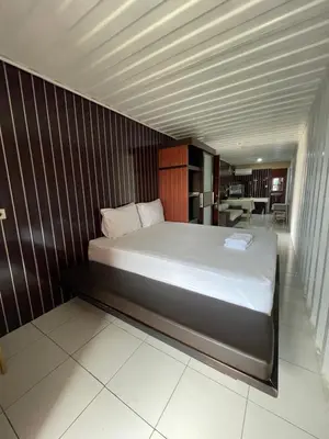 a bedroom with a large bed with a wooden wall at trees inn Bali Denpasar in Denpasar