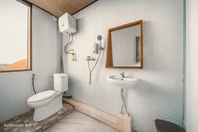 a bathroom with a toilet and a sink and a mirror at trees inn Bali Denpasar in Denpasar