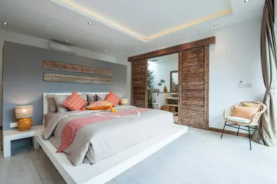 a bedroom with a large bed and a chair at Chill out in a luxurious 4 BR villa Seminyak in Seminyak