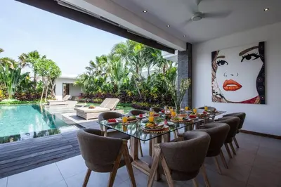 a dining room with a table and chairs and a pool at Chill out in a luxurious 4 BR villa Seminyak in Seminyak
