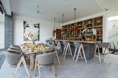 a kitchen with a table and a bar with chairs at Chill out in a luxurious 4 BR villa Seminyak in Seminyak