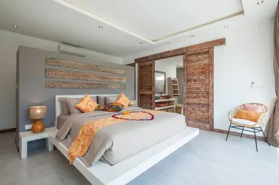 a bedroom with a large bed and a chair at Chill out in a luxurious 4 BR villa Seminyak in Seminyak