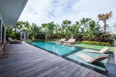 a pool with chaise lounge chairs on a wooden deck at Spacious 4 BR villa Seminyak garden and pool in Seminyak