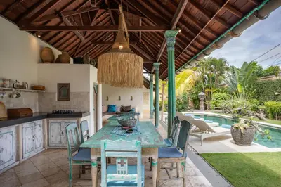 an outdoor kitchen with a table and chairs and a pool at Villa Aisis Seminyak in Seminyak