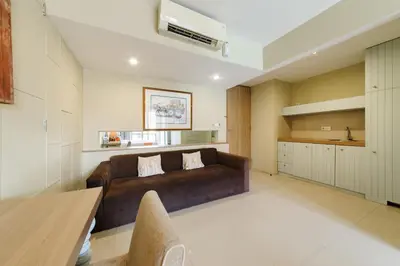 a living room with a brown couch and a kitchen at Sans Vibes Astana Residence Seminyak in Seminyak