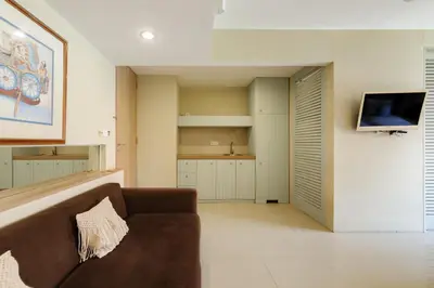 a living room with a couch and a flat screen tv at Sans Vibes Astana Residence Seminyak in Seminyak