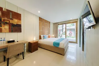 a bedroom with a bed and a desk and a television at Sans Vibes Astana Residence Seminyak in Seminyak