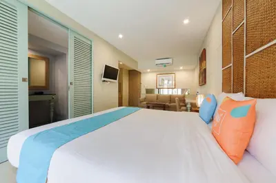 a bedroom with a large white bed with blue and orange pillows at Sans Vibes Astana Residence Seminyak in Seminyak