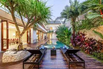 an infinity pool in a villa with palm trees at Villa Ellyne Canggu by Nagisa Bali in Canggu