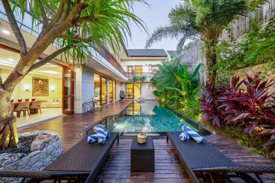 an indoor pool in a villa with palm trees at Villa Ellyne Canggu by Nagisa Bali in Canggu