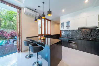 a kitchen with a black counter and stools at Villa Ellyne Canggu by Nagisa Bali in Canggu