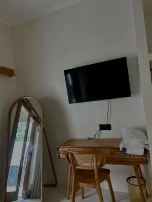 a desk with a television on a wall with a chair at Shine sunset villa in Kerobokan