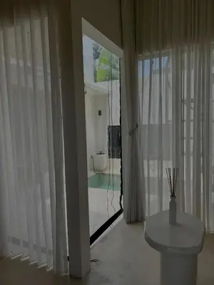 a room with a window with a table and a view of a pool at Shine sunset villa in Kerobokan