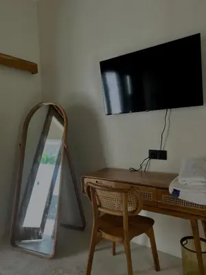 a mirror sitting next to a desk with a television on a wall at Shine sunset villa in Kerobokan