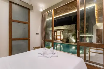 a bedroom with a bed and a swimming pool at Villa Tropea by BaliSuperHost in Seminyak