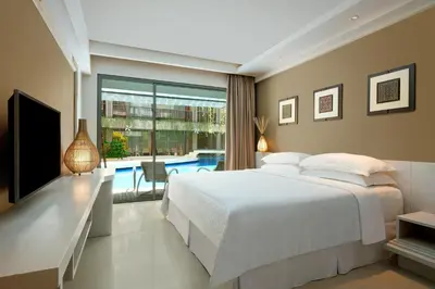 a bedroom with a bed and a television and a pool at Four Points by Sheraton Bali, Kuta in Kuta