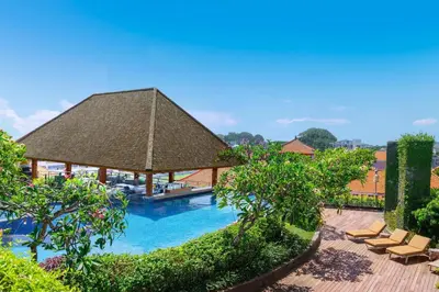 a swimming pool with chairs and a large roof at Four Points by Sheraton Bali, Kuta in Kuta