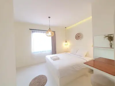 a white bedroom with a bed and a desk at Villa Kiara Sanur in Sanur