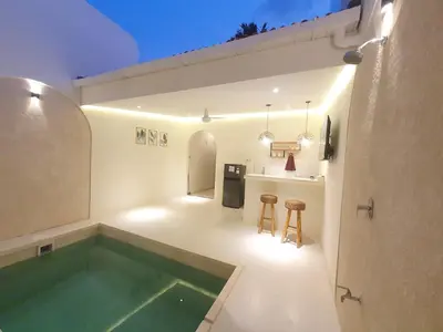 a bathroom with a swimming pool and two stools at Villa Kiara Sanur in Sanur